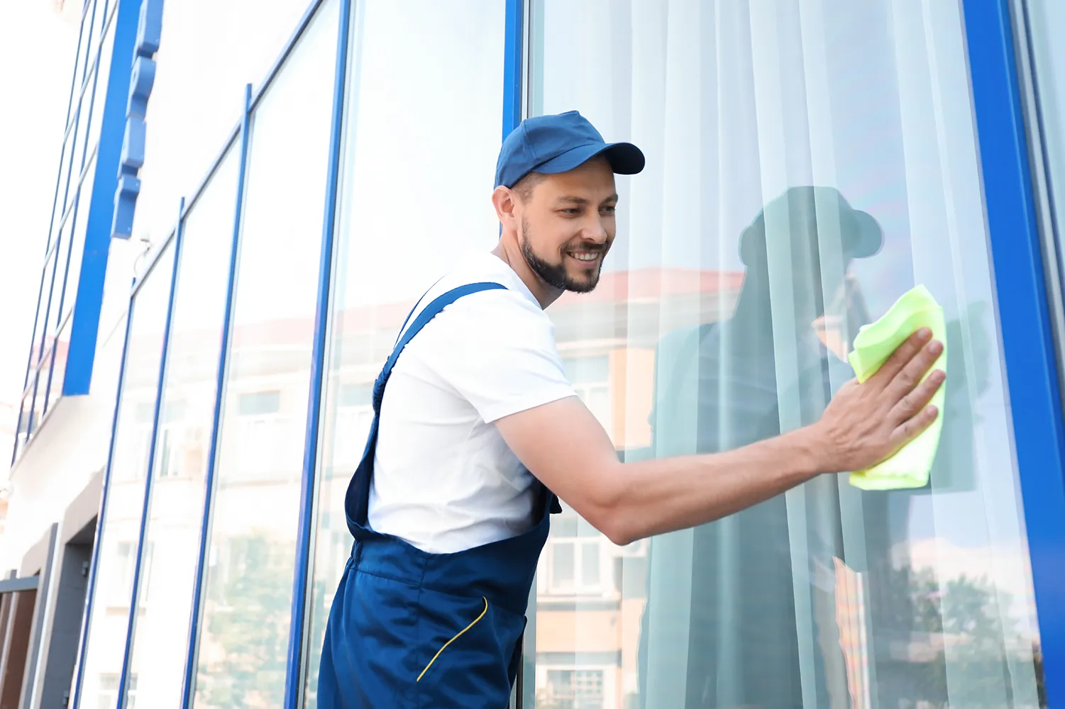 Männlicher Arbeiter putzt Fensterglas von außen von Ferdi Clean